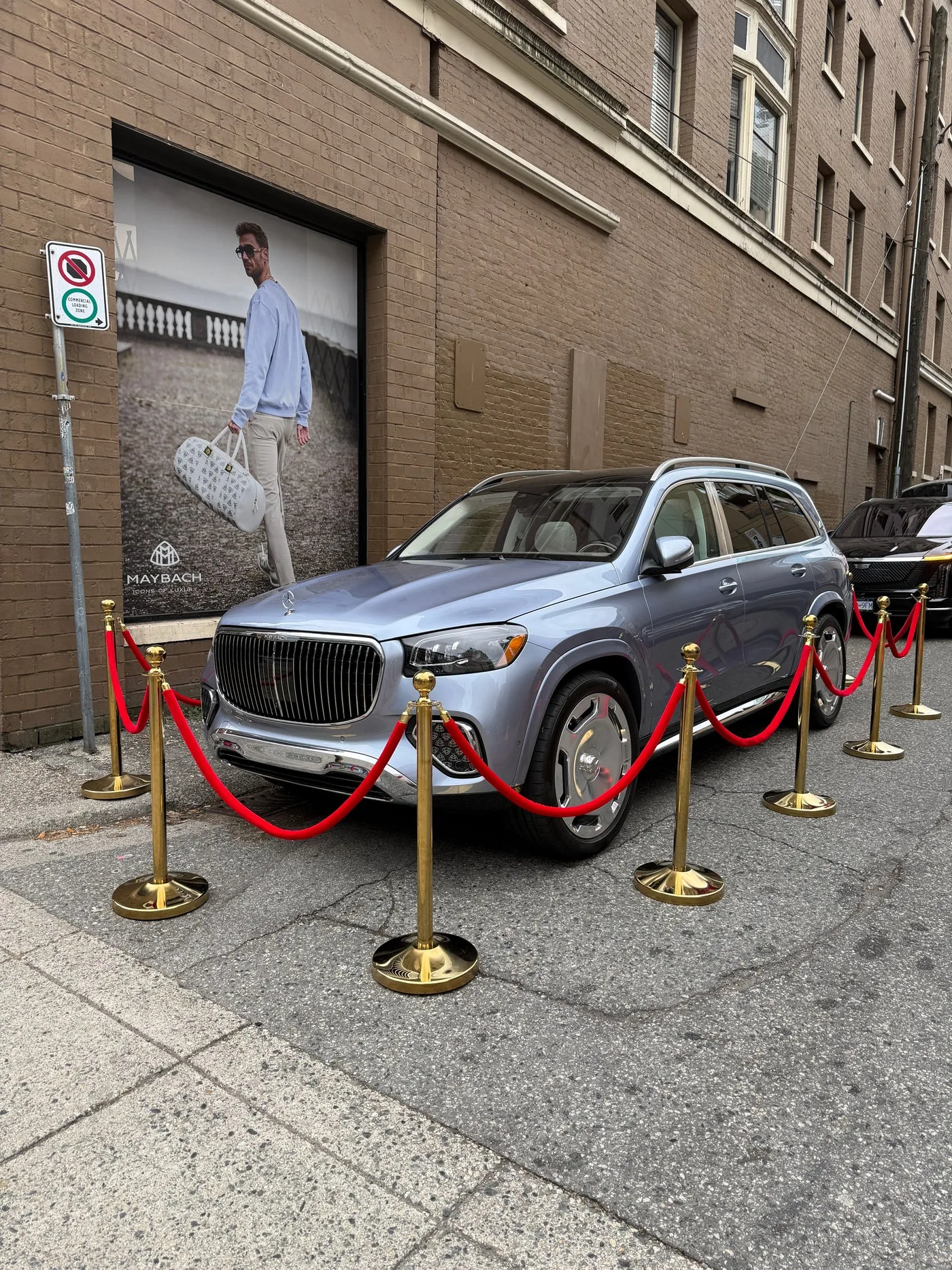 Gold stanchions and red ropes cordoning a silver SUV parked on a city street